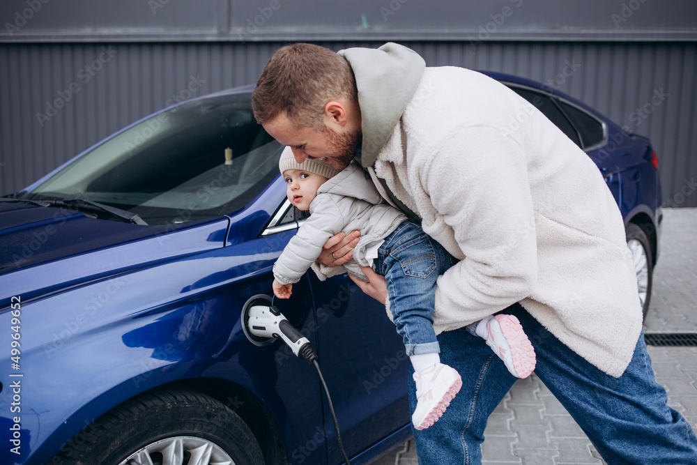 A father with his young daughter is charging an electric car