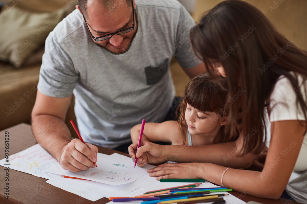 Fototapeta premium They encourage creative play in their home. Shot of a mother and father drawing together with their young daughter at home.