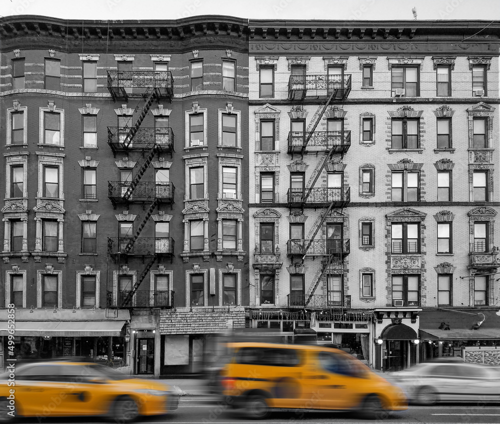 Yellow taxis driving past old apartment buildings in the East Village neighborhood of New York City in black and white