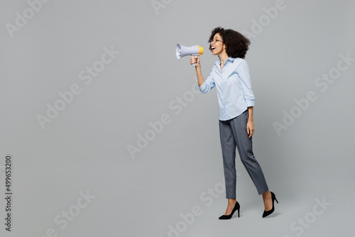 Full body young employee business corporate lawyer woman of African American ethnicity in shirt work in office hold scream in megaphone announces discounts sale Hurry up isolated on grey background. © ViDi Studio