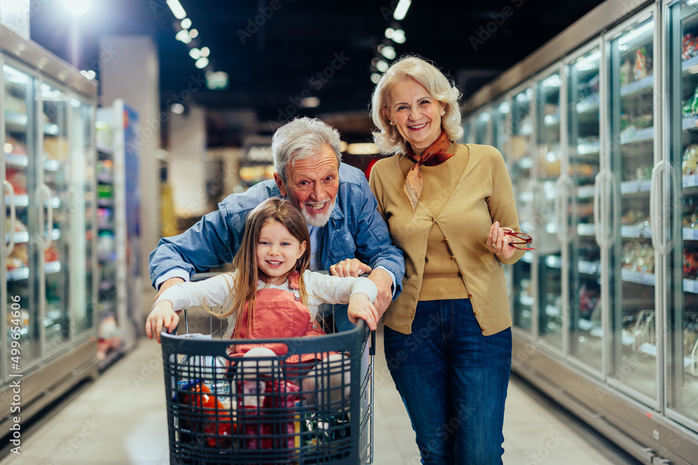 Senior couple and granddaughter shopping in supermarket