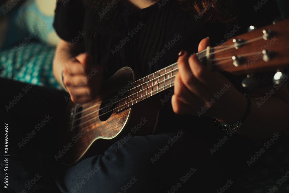 Fototapeta premium Mujer tocando ukulele en su habitación. Concepto de musica.