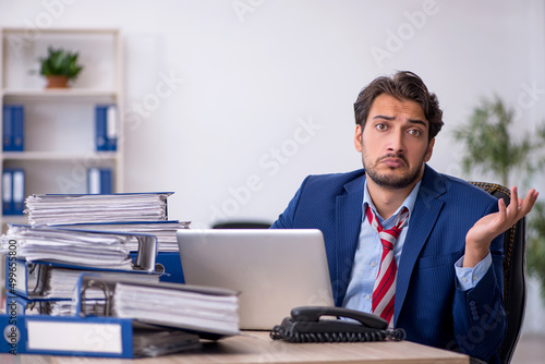 Young male employee and too much work in the office