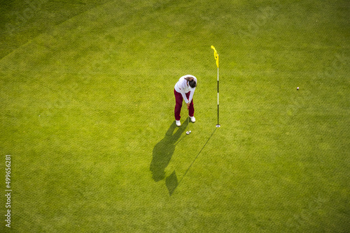 A young woman playing golf, photographed from above.