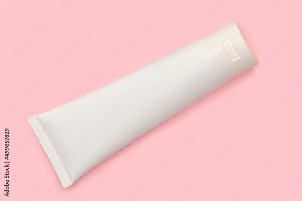 White cosmetic bottle on a pink background. Cream for body care. White cosmetic bottle on a pink background. Cream for body care.