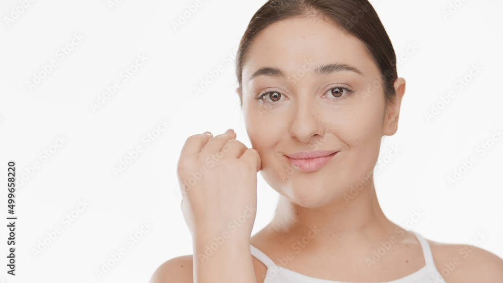 Beauty portrair of young attractive Caucasian woman who touches her face looking at camera on white background | Face care concept Beauty portrair of young attractive Caucasian woman who touches her face looking at camera on white background | Face care concept