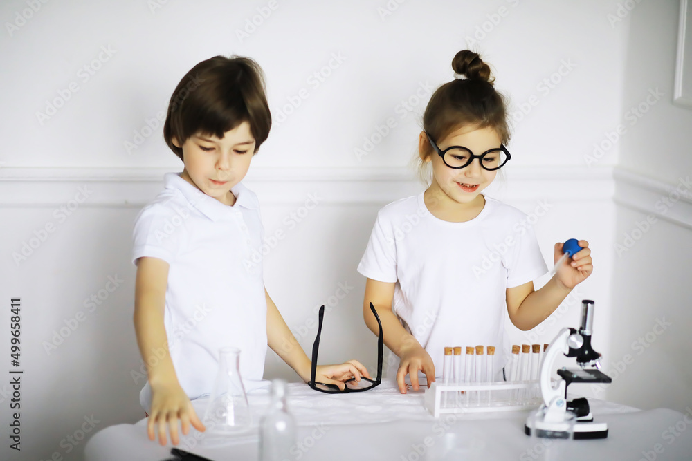 Two cute children at chemistry lesson making experiments on white background Two cute children at chemistry lesson making experiments on white background