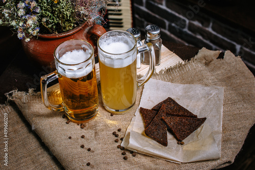 Beer in a large mug, standing on the table. Fried toast from black bread in a plate. photo