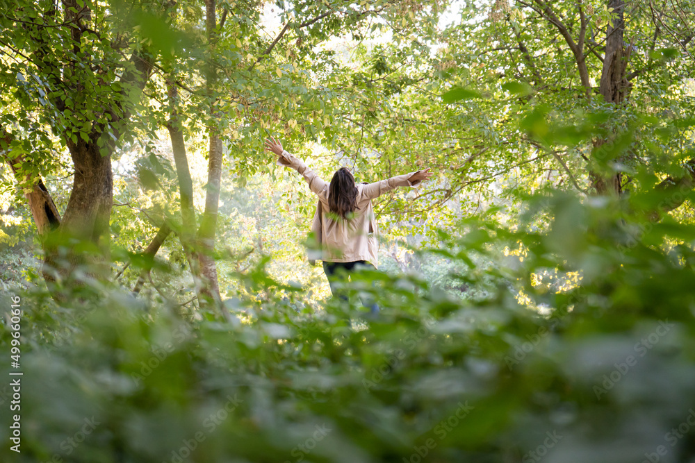 Obraz premium woman with open arms wearing a raincoat in the forest
