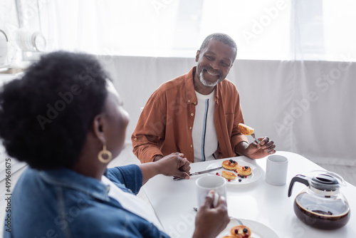 joyful and senior african american couple holding hands while having breakfast.