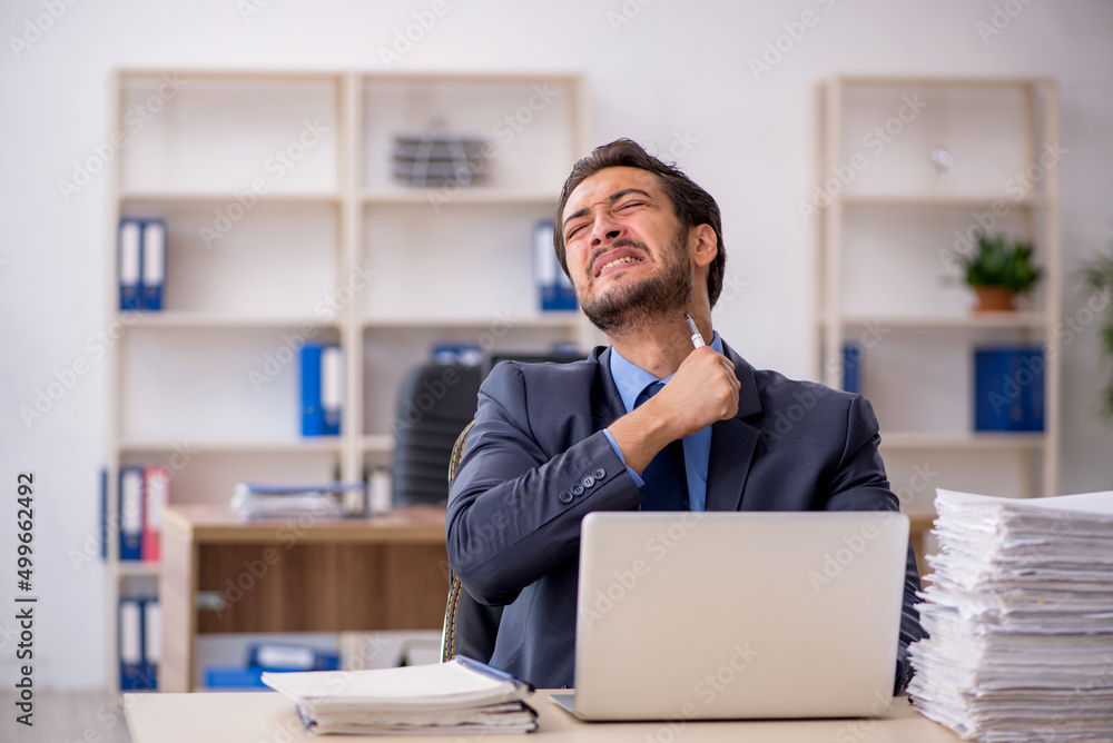 Obraz premium Young male employee and too much work in the office