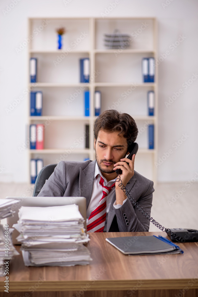 Young male employee unhappy with excessive work in the office Young male employee unhappy with excessive work in the office