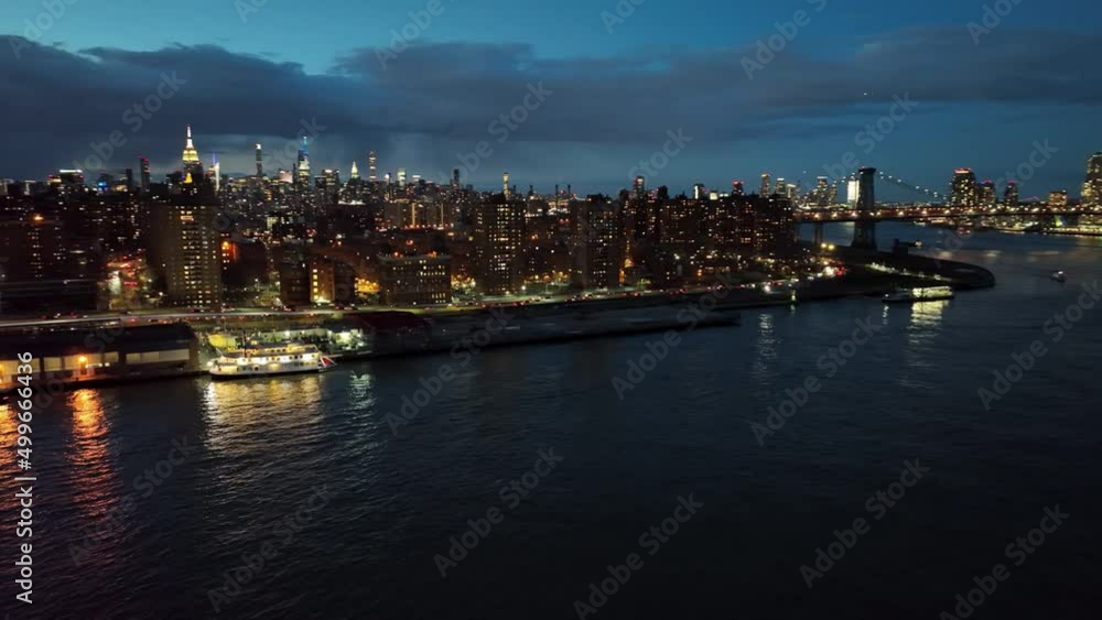 aerial panning Manhattan island at night skyline buildings lights from East River in NYC aerial panning Manhattan island at night skyline buildings lights from East River in NYC