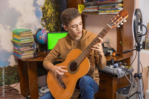 boy playing guitar sitting in his room