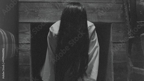 Scary Ghost Woman Crawling or Walking In Horror Halloween Scene . Droning television inside dark empty room . Little girl in white sundress . The ring movie theme . Girl with long black hair. Close up Scary Ghost Woman Crawling or Walking In Horror Halloween Scene . Droning television inside dark empty room . Little girl in white sundress . The ring movie theme . Girl with long black hair. Close up