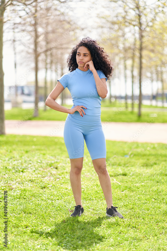 Sad girl in a blue sportswear holds her head at the park