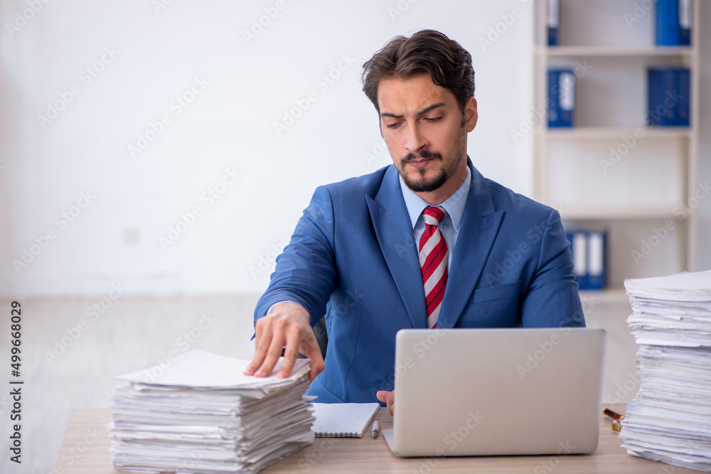Young male employee and too much work in the office Young male employee and too much work in the office