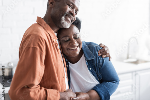 happy and senior african american couple holding hands and hugging at home.