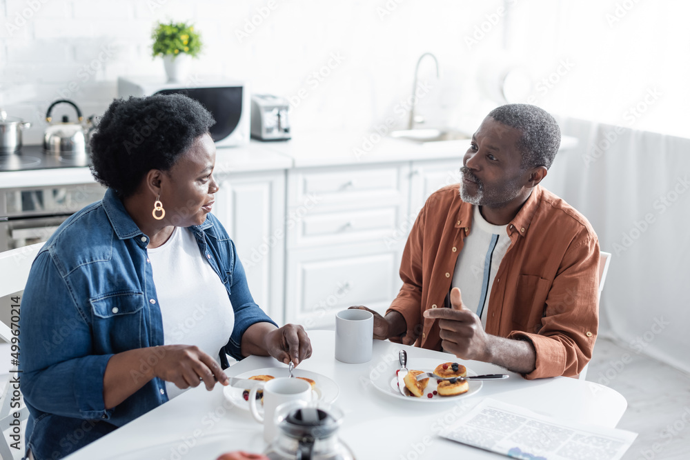senior african american couple talking during breakfast in kitchen.