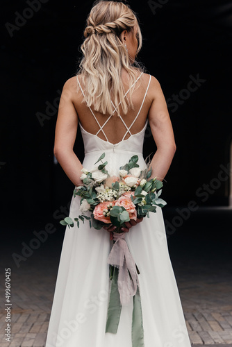 concept and stylish bride holding a beautiful wedding bouquet behind her back