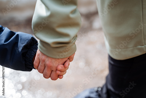Hands close-up, mother holding the child's hand, friendship in the family, closing fingers together, family walk in nature.