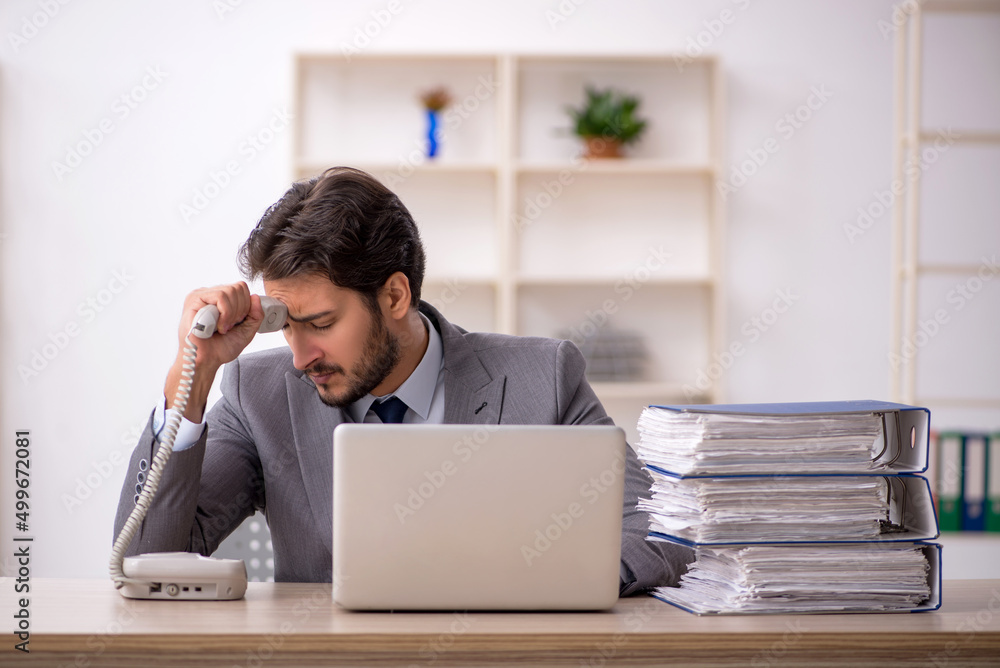 Young male employee and too much work in the office Young male employee and too much work in the office