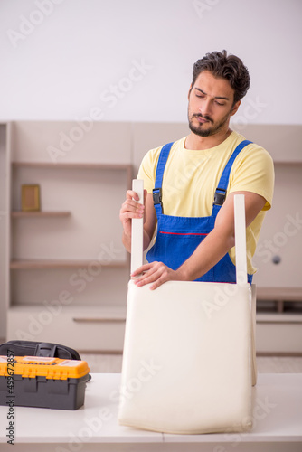 Young male carpenter repairing chair at home