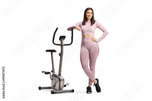 Fototapeta Naklejka Na Ścianę i Meble -  Young fit woman in sportswear leaning on a stationary bike