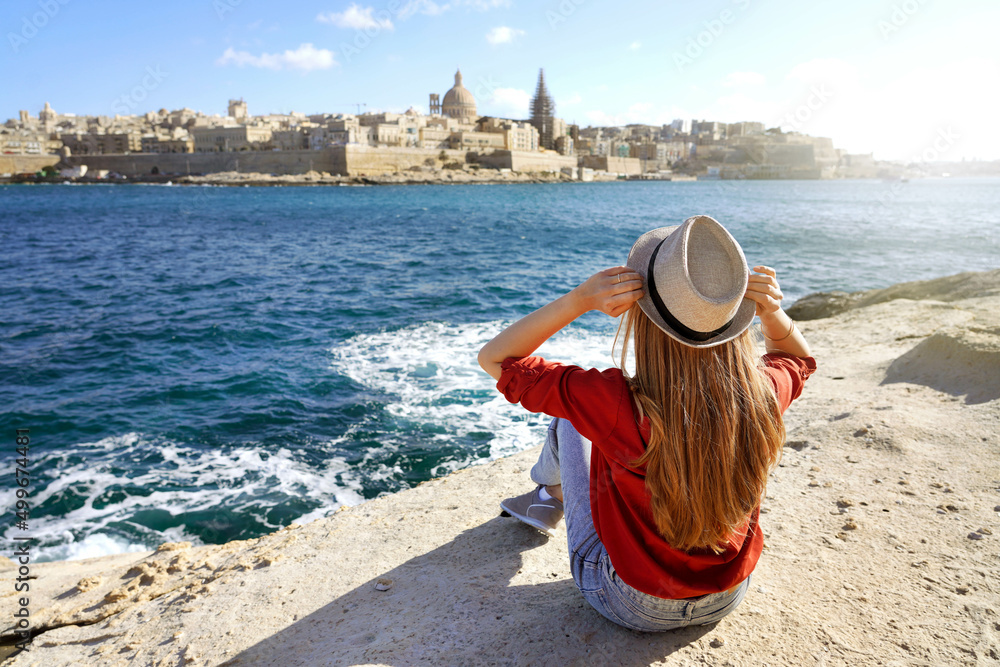 Obraz na płótnie Young traveler woman holds hat looking at Valletta old town travel destination in Malta w salonie