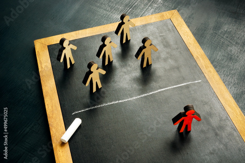 Social exclusion concept. Figurines and a chalk line separating them. photo