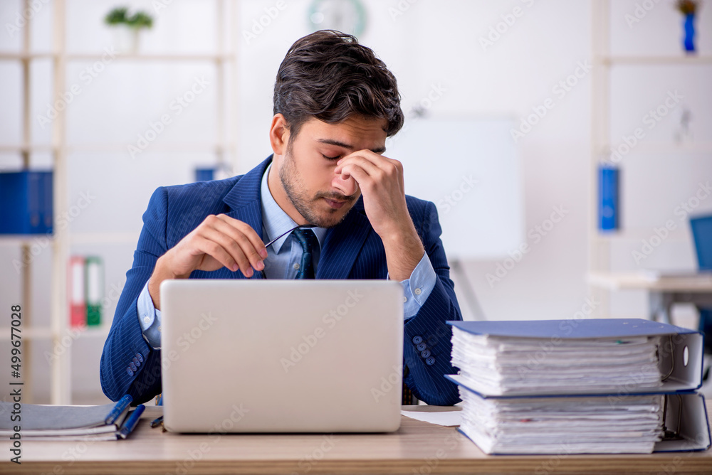 Young businessman employee and too much work in the office Young businessman employee and too much work in the office