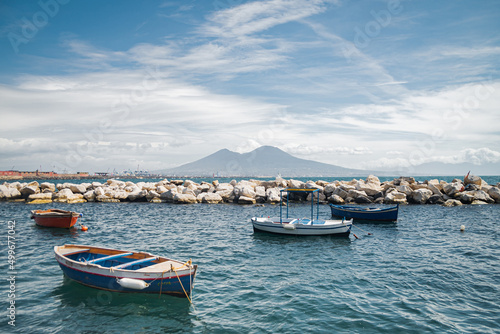 Calm blue Tyrrhenian Sea. View from the embankment of Naples to Mount Vesuvius volcano. Pleasure boats moored near the shore and stone breakwaters. © Alona Dudaieva