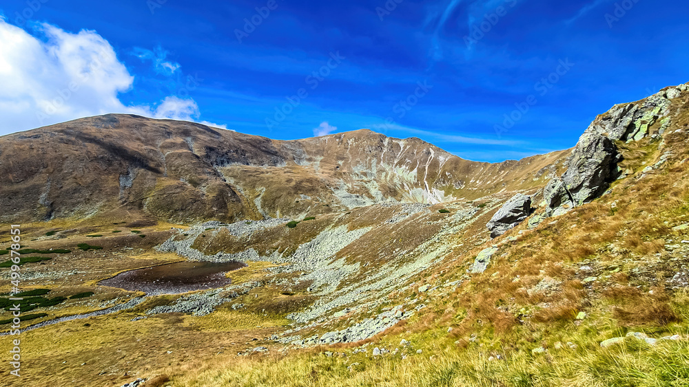 Scenic view from lake Goldlacke on yellow hills of Lower Tauern mountain range, Styria, Austria, Europe. Sunny autumn day in Seckau Alps. Scenic hiking trail to Seckauer Zinken on dry, bare terrain Scenic view from lake Goldlacke on yellow hills of Lower Tauern mountain range, Styria, Austria, Europe. Sunny autumn day in Seckau Alps. Scenic hiking trail to Seckauer Zinken on dry, bare terrain