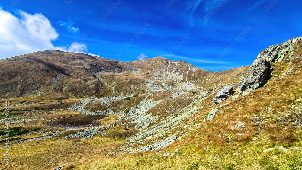 Scenic view from lake Goldlacke on yellow hills of Lower Tauern mountain range, Styria, Austria, Europe. Sunny autumn day in Seckau Alps. Scenic hiking trail to Seckauer Zinken on dry, bare terrain