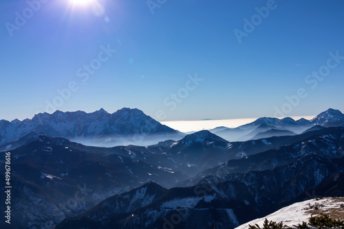 Panoramic view on snow capped mountain peaks of Karawanks in Carinthia, Austria. Julian Alps. Winter wonderland in the Austrian Alps, Europe. Ski tour, snow shoe hiking. Hochobir. Blue misty hills. photo