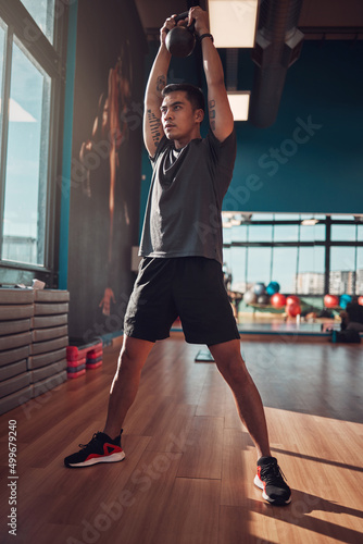 Put everything into each workout. Shot of a young man working out using a kettlebell in the gym.