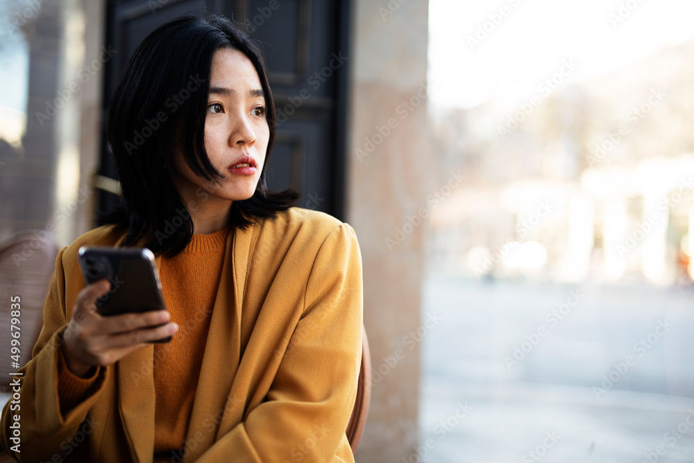 Happy Chinese girl checking phone. Beautiful young girl typing a message.. Happy Chinese girl checking phone. Beautiful young girl typing a message..