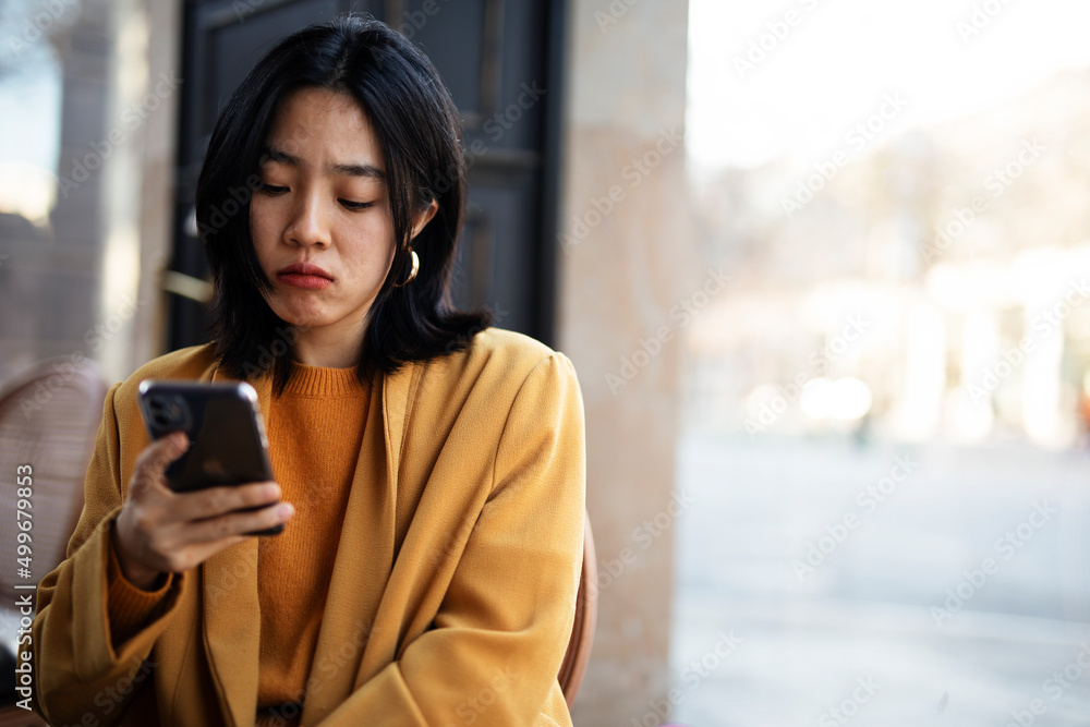 Happy Chinese girl checking phone. Beautiful young girl typing a message.. Happy Chinese girl checking phone. Beautiful young girl typing a message..