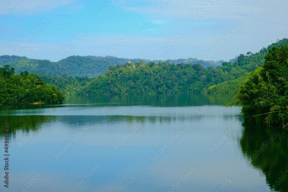 Calm view of dam water surrounded with green trees in Kuala Kubu Bharu, Selangor, Malaysia.