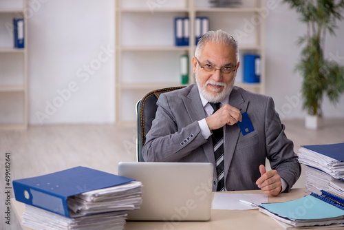 Old male employee holding credit card in the office