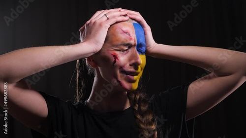 girl with the flag of Ukraine on her face and with wounds holding her head and screaming in hysterics