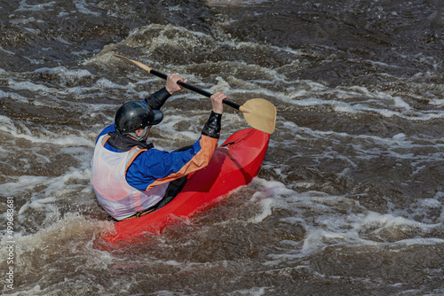 A series of images. Athletes in kayaks and kayaks conquer the stormy waters of the river. Dressed in waterproof clothes and helmets. They hold an oar in their hands. Motion blur