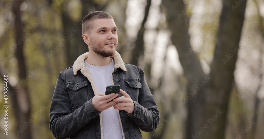 Smiling man use smartphone walking in the park Smiling man use smartphone walking in the park