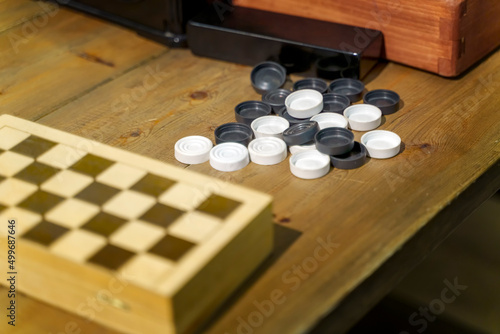 Checkers next to a chessboard on a wooden table photo