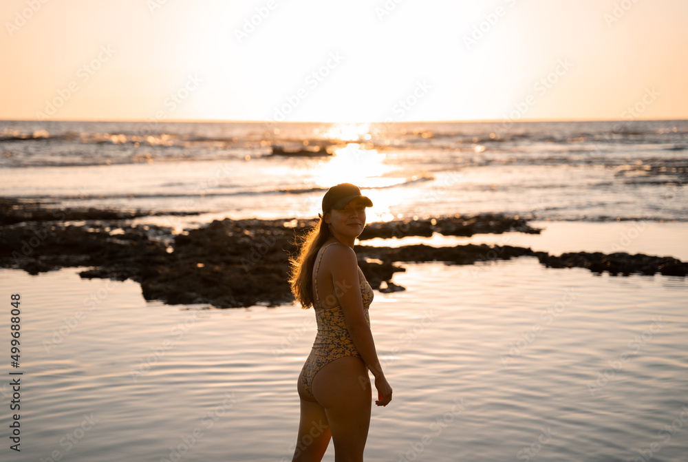 Young blonde woman is posing happily wwearing a cap on the beach during a summer sunset Young blonde woman is posing happily wwearing a cap on the beach during a summer sunset