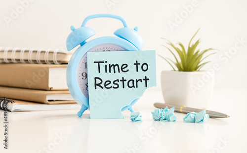 TIME TO RESTART text on page on a torn sticker pasted on an alarm clock