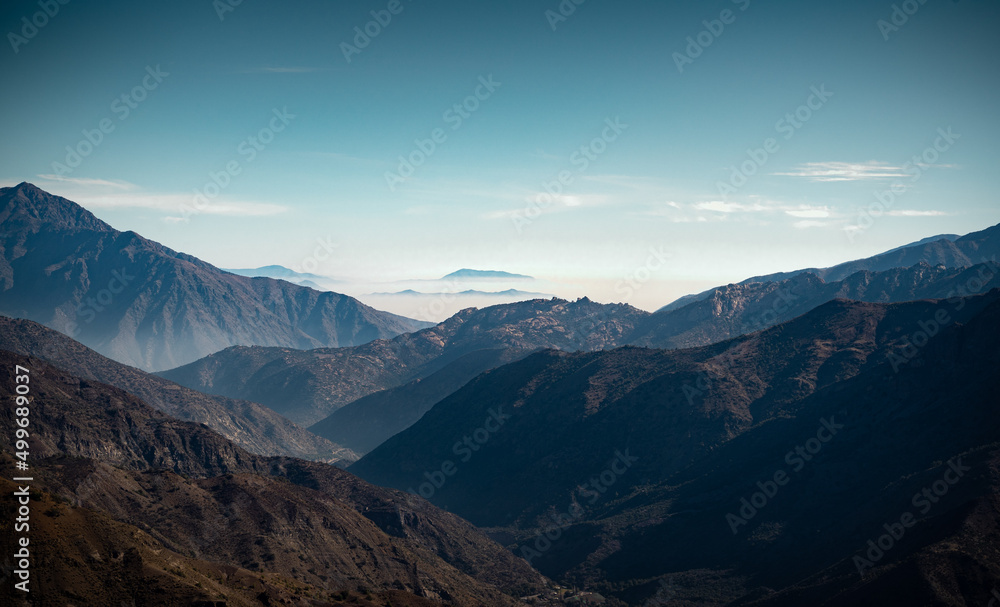 Horizontal view of mountain range in the distance getting lost in the fog in Cajon del Maipo, Chile.