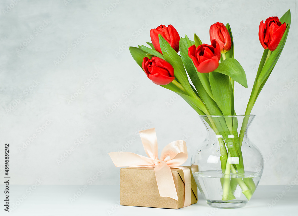 Obraz premium vase with red tulips and gift box on light concrete background