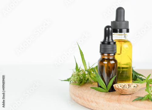 CBD oil, cannabis leaves and seeds on wooden stand and light copy space