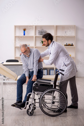 Old man in wheelchair visiting young male doctor